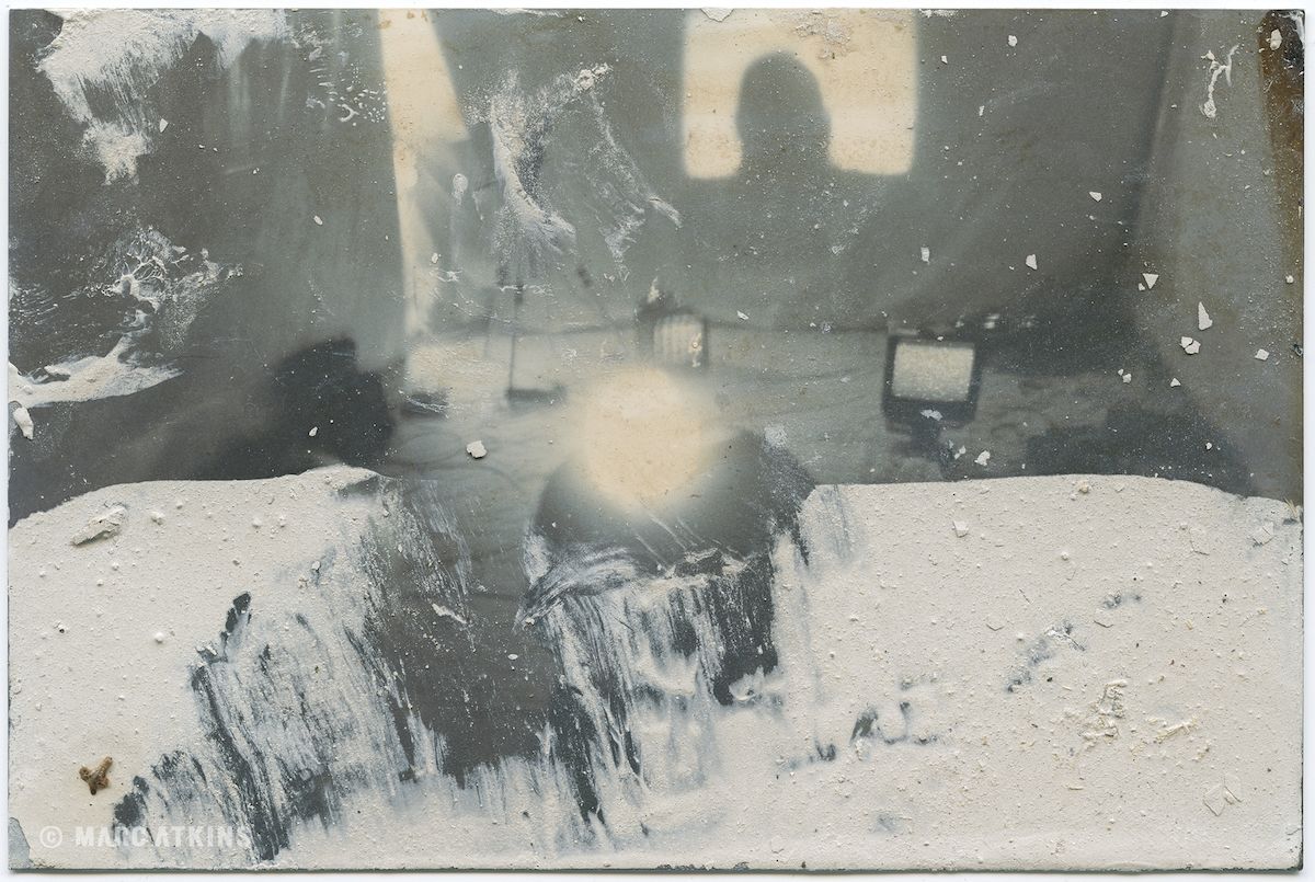 Muted grey image with a bright circular light and layered surface marks