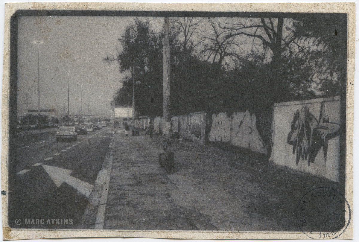 Black-and-white street scene with pedestrians, trees and buildings